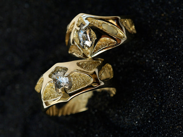 custom made 14k yellow gold wedding bands with salt and pepper diamonds on a black background