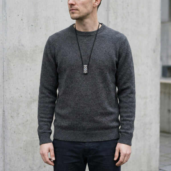 Man wearing a gray sweater against a concrete wall, mens handmade silver pendant 