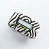 A sterling silver statement ring with a dark green stone set in a rectangular frame. The ring has a textured design with swirling lines. Geo collection by Moonique