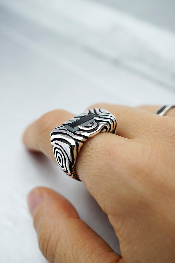 A sterling silver statement ring with a dark green stone set in a rectangular frame. The ring has a textured design with swirling lines. Geo collection by Moonique